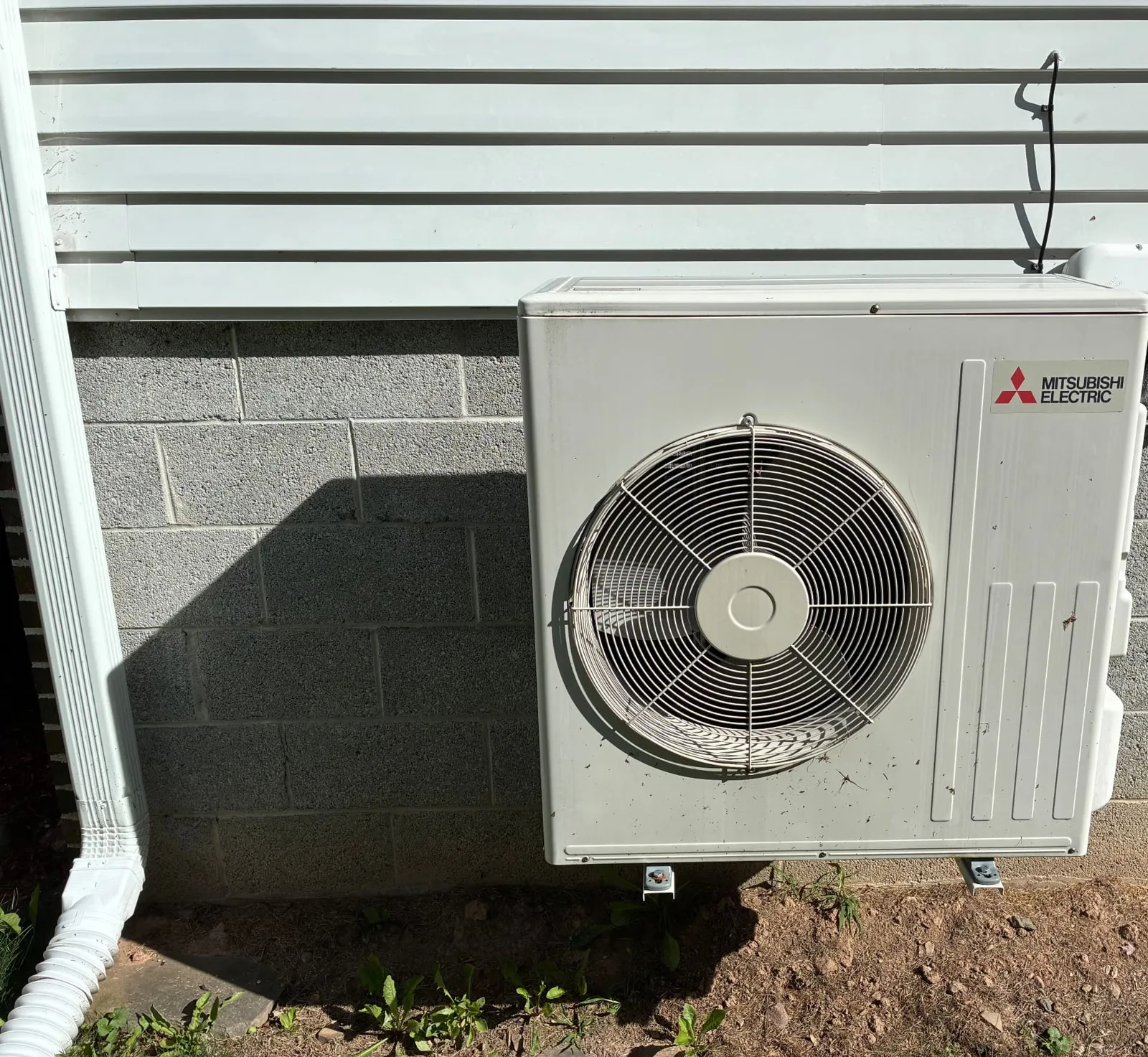 Mitsubishi Electric outdoor unit installed against a block foundation