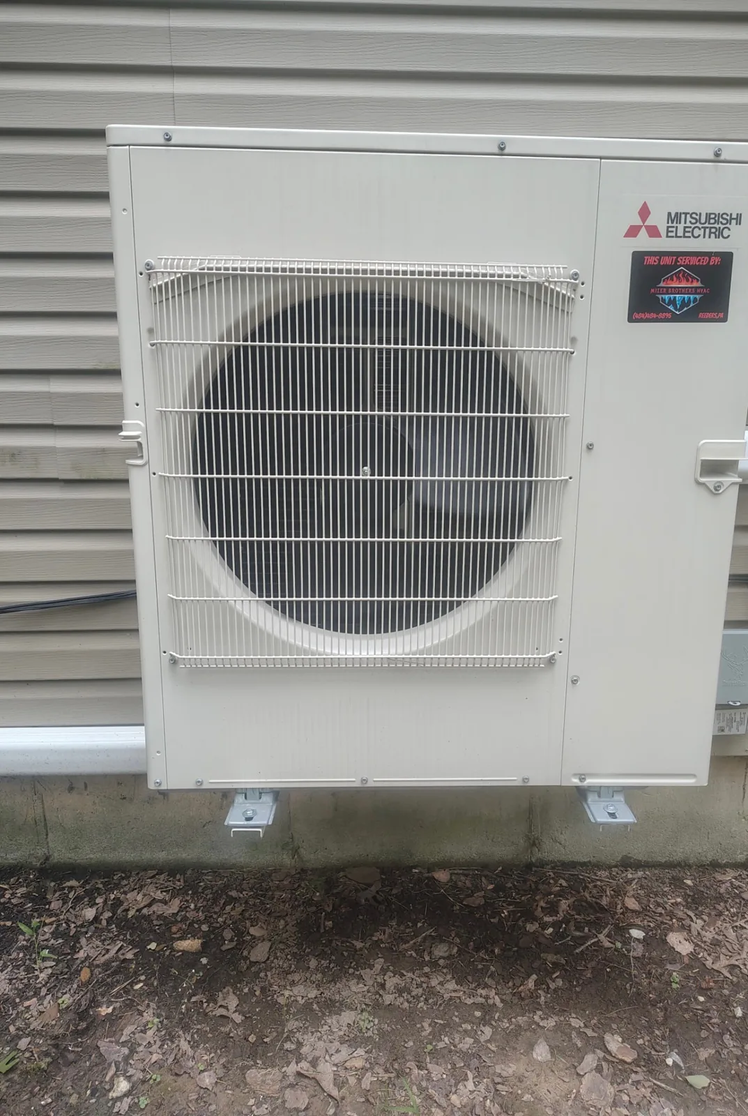 Mitsubishi Electric mini-split outdoor condenser mounted on wall brackets at a customer's home