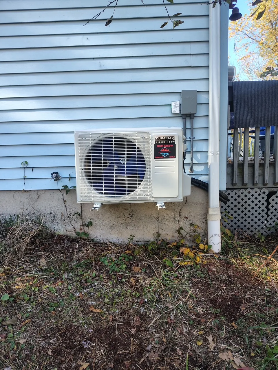 Mitsubishi Electric mini-split condenser wall-mounted on blue siding at a customer's home